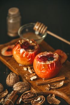 baked apples with cottage cheese with berries and nuts, topped with honey and sprinkled with cinnamon. on a wooden surface in a rustic style