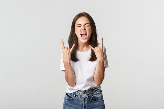 Joyful good-looking girl showing rock-on gesture and enjoying concert.