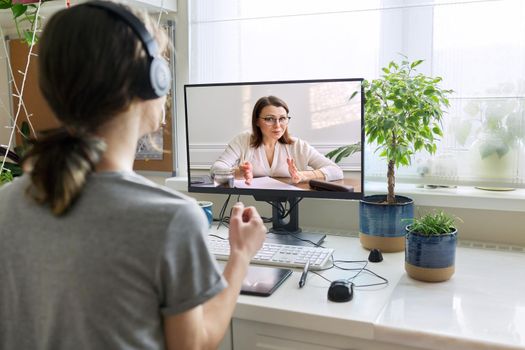 Online consultation of male teenager by social worker psychologist behavior teacher. Virtual meeting, using video call on home computer. Technologies, communication, help, mental health of adolescents