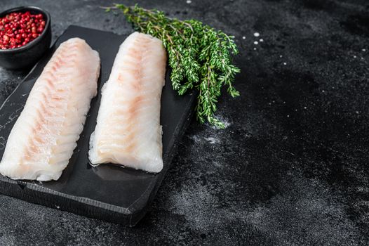 Raw cod loin fillet fish on marble board. Black background. Top view. Copy space.