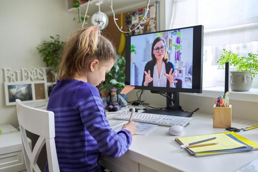 Young child girl studying with teacher remotely on computer using video call, an individual online lesson, videoconference application. Education, technology, children, pre-teens, e-learning concept