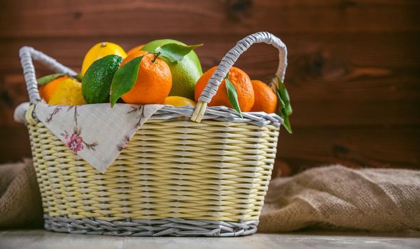 citrus fruits in a wicker basket on a wooden background