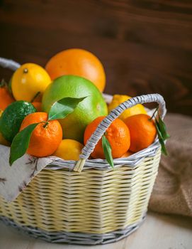 citrus fruits in a wicker basket on a wooden background