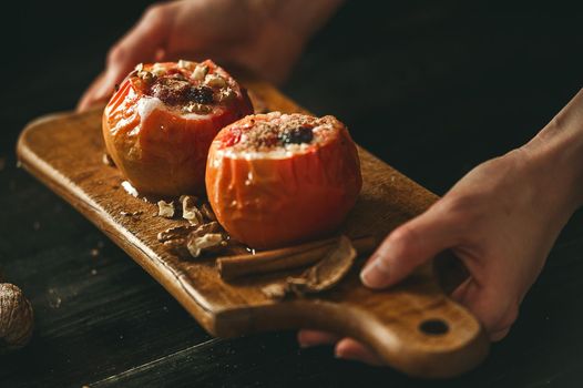 baked apples with cottage cheese with berries and nuts, topped with honey and sprinkled with cinnamon. on a wooden surface in a rustic style