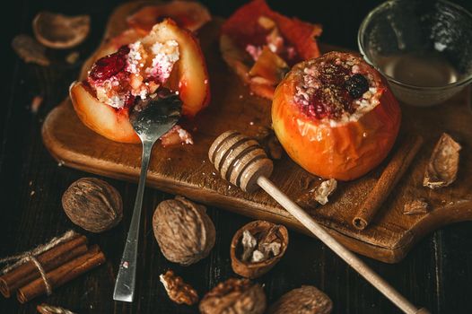 baked apples with cottage cheese with berries and nuts, topped with honey and sprinkled with cinnamon. on a wooden surface in a rustic style