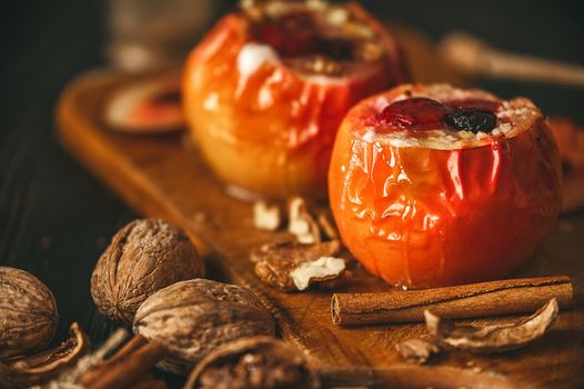 baked apples with cottage cheese with berries and nuts, topped with honey and sprinkled with cinnamon. on a wooden surface in a rustic style