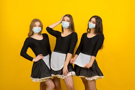Beautiful sexy women in maid clothes posing in studio in covid protective mask