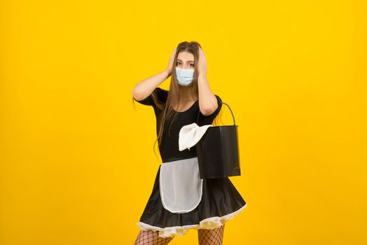 Beautiful sexy woman in maid clothes posing in studio in covid protective mask