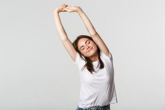 Portrait of relaxed carefree brunette girl stretching with satisfied smile.