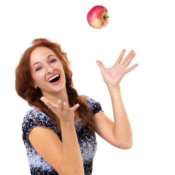 Smiling happy girl throwing up red apple in the air. Portrait of joyful girl in summer dress sitting on isolated white background. Healthy eating and diet concept