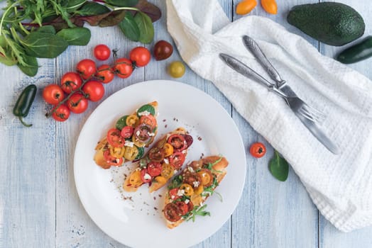 Bruschetta with cheese, basil, arugula and cherry tomatoes