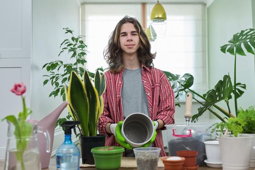 Green eco hobby of young male, teenager showing plant, soil, expanded clay, soil additives perlite vermiculite at camera, recording video for plant vlog blog. Eco green trends, modern city apartments