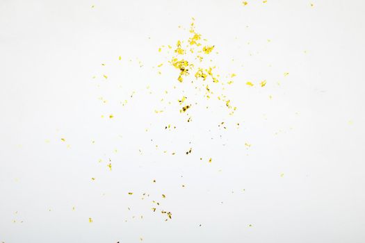 Top view of golden glossy spangles scattered chaotically on white background in studio
