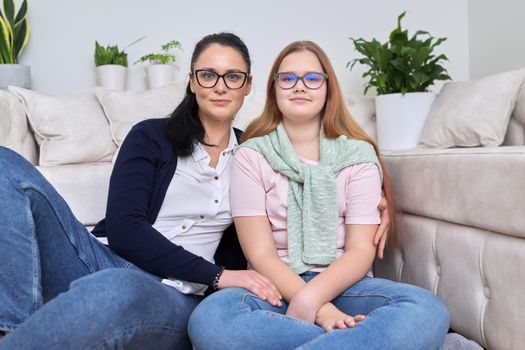 Portrait of happy mom and daughter, mother hugging her teenage daughter, sitting at home together. Mother's day, love, relationship, family concept