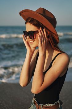 cheerful woman in sunglasses and a hat by the ocean walk summer. High quality photo