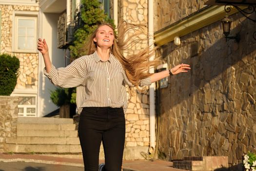 Happiness joy freedom, young beautiful woman running along city street, female with flying hair running through city in sunset light