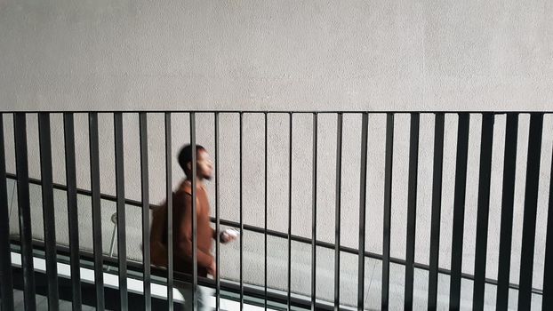 a silhouette of a black man descending the stairs down behind the metal railing