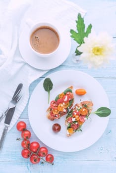 Bruschetta with cheese, basil, arugula and cherry tomatoes and a glass of white wine