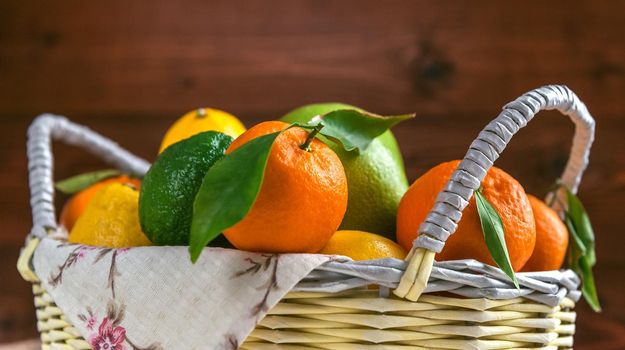 citrus fruits in a wicker basket on a wooden background