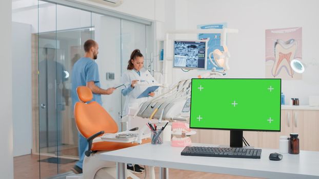 Horizontal green screen on computer in dentist office while specialists using equipment for dental care. Monitor with chroma key and isolated mockup template in office for teethcare.