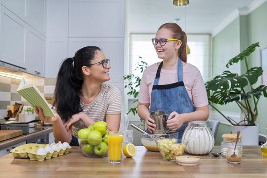 Family, relationships, lifestyle. Mom and teen daughter cooking apple pie together at home kitchen
