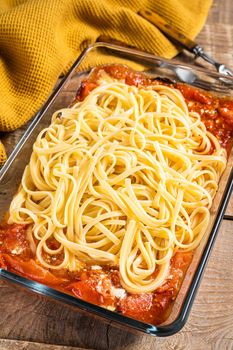 Oven baked feta Spaghetti pasta in baking dish. Wooden background. Top view.