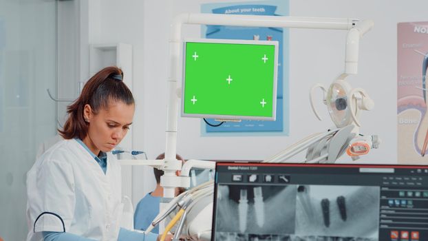 Woman working as dentist with green screen and x ray scan for teethcare in dental cabinet. Oral care specialist analyzing chroma key with isolated mockup template and teeth radiography