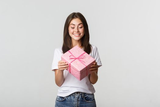 Happy cute young birthday girl, smiling and looking at b-day gift.