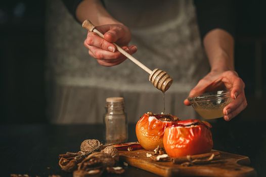 baked apples with cottage cheese with berries and nuts, topped with honey and sprinkled with cinnamon. on a wooden surface in a rustic style