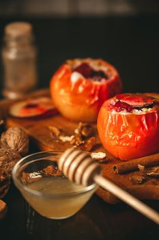 baked apples with cottage cheese with berries and nuts, topped with honey and sprinkled with cinnamon. on a wooden surface in a rustic style