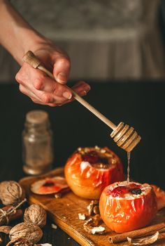 baked apples with cottage cheese with berries and nuts, topped with honey and sprinkled with cinnamon. on a wooden surface in a rustic style