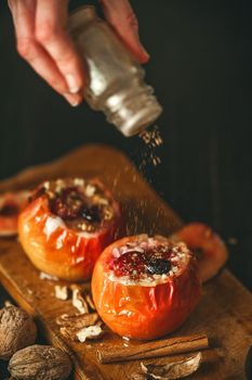 baked apples with cottage cheese with berries and nuts, topped with honey and sprinkled with cinnamon. on a wooden surface in a rustic style