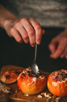 baked apples with cottage cheese with berries and nuts, topped with honey and sprinkled with cinnamon. on a wooden surface in a rustic style