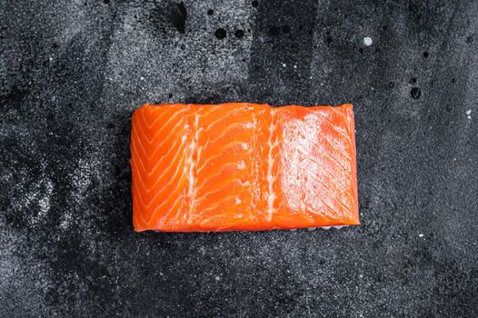 Raw salmon fillet steaks on kitchen table. Black background. Top view.