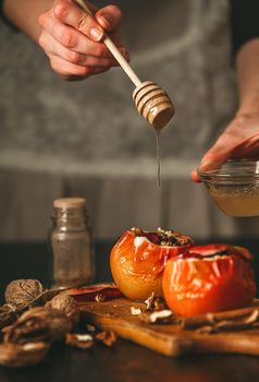 baked apples with cottage cheese with berries and nuts, topped with honey and sprinkled with cinnamon. on a wooden surface in a rustic style