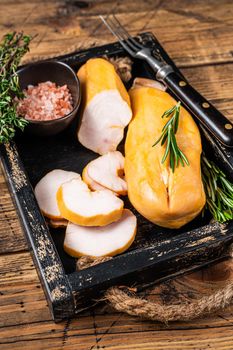 Hot Smoked chicken breast fillet meat on a wooden board with herbs. wooden background. Top view.