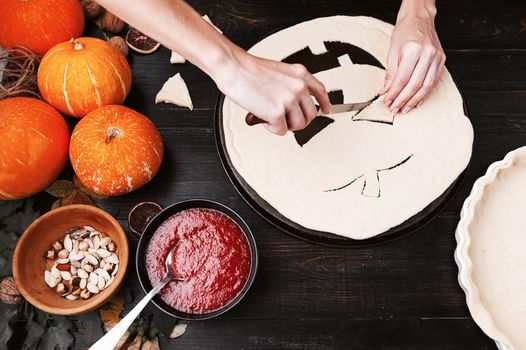 Chef cooks a pie for Halloween with a filling of pumpkin-strawberry jam and peaches