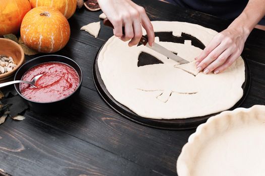 Chef cooks a pie for Halloween with a filling of pumpkin-strawberry jam and peaches