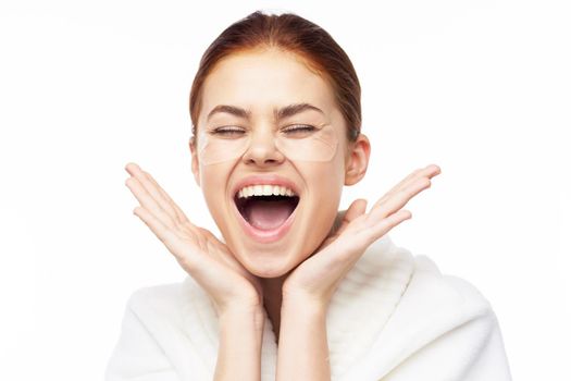 Woman in white robe posing fun skin care patches on face. High quality photo