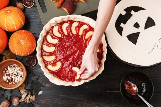 Chef cooks a pie for Halloween with a filling of pumpkin-strawberry jam and peaches