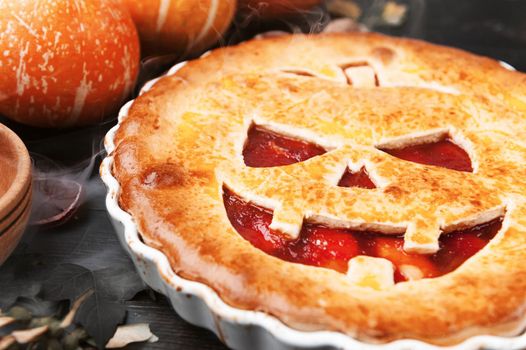 Delicious homemade pie for halloween with a filling of pumpkin-strawberry jam and peaches