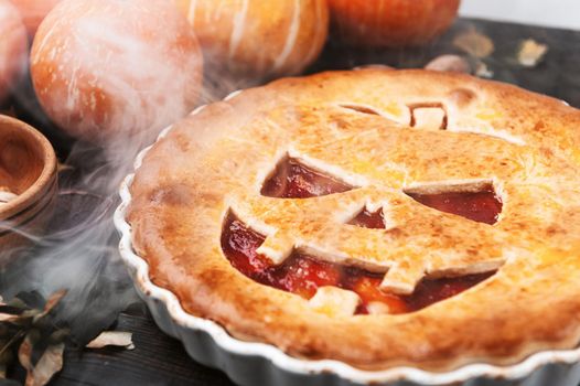 Delicious homemade pie for halloween with a filling of pumpkin-strawberry jam and peaches