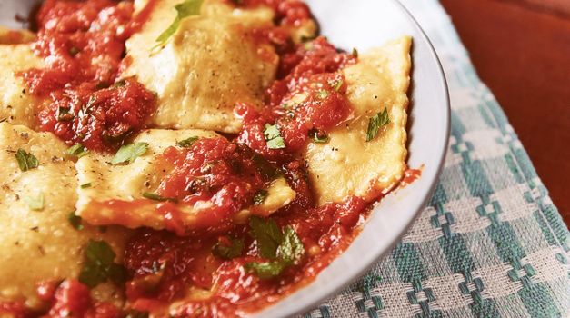 Delicious ravioli with tomato sauce in a plate on a wooden background