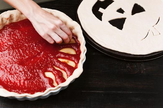 Chef cooks a pie for Halloween with a filling of pumpkin-strawberry jam and peaches