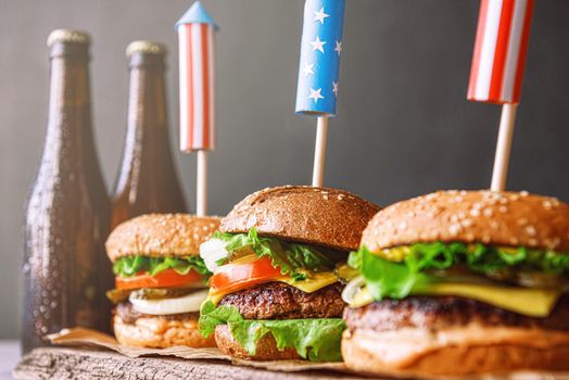 three fresh and juicy burgers with American flag-style fireworks inserted into them. bbq concept picnic to celebrate independence day