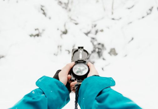 Female hands with a compass in winter outdoor on background of snow. Point of view shot.