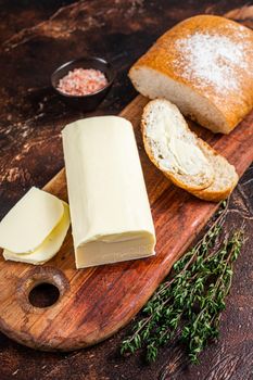 Butter spread and foodstuff toasts on a wooden cutting board. Dark background. Top view.