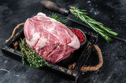 Raw pork neck meat piece for Chop steak in wooden tray with herbs. Black background. Top view.