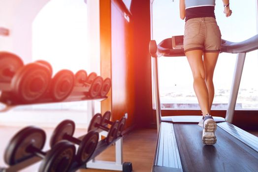 girl on the morning run on the treadmill in the gym in front of a large window on the background of the sea