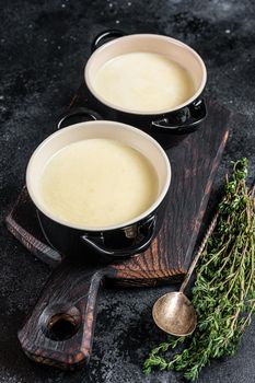 Potato cream soup in bowls on kitchen table. Black background. Top view.